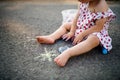 Unrecognizable toddler girl outdoors in countryside, chalk drawing on road. Royalty Free Stock Photo