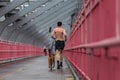 Unrecognizable topless recreational runner and a dog at Williamsburg bridgein New York CIty, USA. Royalty Free Stock Photo