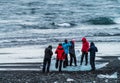 Unrecognizable tourists taking photos over iceberg on diamond beach
