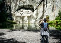 Unrecognizable tourist taking picture with his phone of the Lucerne Lion monument carving symbol of Lucerne city Switzerland
