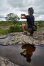 Unrecognizable traveler and blogger holding a phone and streaming in the natural environment