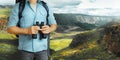 Young Traveler Man With Backpack And Binoculars Seeking Direction In Mountains. Hiking Tourism Journey Concept