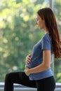 Unrecognizable unknown Caucasian millennial young female prenatal pregnant mother in casual outfit standing alone holding hands Royalty Free Stock Photo