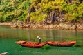 Unrecognizable vietnamese woman rowing boats that bring tourists traveling inside limestone cave with limestone island Royalty Free Stock Photo