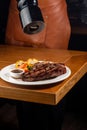 unrecognizable Waiter peppering steak in a plate Royalty Free Stock Photo