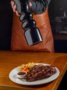 unrecognizable Waiter peppering steak in a plate Royalty Free Stock Photo