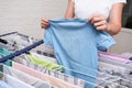 Unrecognizable woman collecting dry clean clothes from a drying rack and putting it in stack for ironing