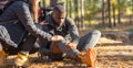 Unrecognizable woman comforting injured black guy, backpacking together by forest