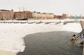 Unrecognizable woman comming out of cold water at Helsinki harbour. Snowed landscape