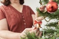 Unrecognizable woman decorating a Christmas tree, hanging a bell on a branch Royalty Free Stock Photo