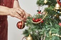 Unrecognizable woman decorating a Christmas tree, hanging a bell on a branch Royalty Free Stock Photo