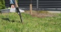 Unrecognizable woman digs a hole for a tree with a shovel in the garden near the house. The female plants a young Royalty Free Stock Photo