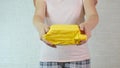 An unrecognizable woman giving yellow package, parcell to a camera, shipping and delivery concept