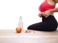 Unrecognizable woman grabbing her love handles on white background with measuring tape, an apple and a bottle of water Royalty Free Stock Photo