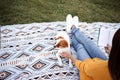 unrecognizable woman having fun with jack russell dog in park, sitting on blanket during autumn season. Woman reading a book while Royalty Free Stock Photo