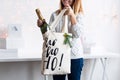 Unrecognizable woman holding Christmas gift with champagne in cloth bag. Happy winter holidays. Presents for Christmastime Royalty Free Stock Photo