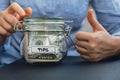 Unrecognizable woman holding Glass jar full of American currency dollars cash banknote with text TIPS. Preparation