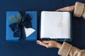 Unrecognizable woman holding and unpacking gift in blue box. Happy winter holidays. Presents for Christmastime celebration. Royalty Free Stock Photo