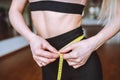 Unrecognizable woman measuring her athletic fit abdomenbelly with yellow tape. Successful weight loss concept Royalty Free Stock Photo