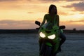 Unrecognizable woman on motorcycle at sunset