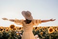 Unrecognizable woman with open arms in sunflowers field. Yellow colors, warm toning. Free girl in straw hat and retro Royalty Free Stock Photo