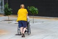 Unrecognizable woman pushing a wheelchair with a disabled person