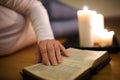 Unrecognizable woman reading Bible. Burning candles next to her. Royalty Free Stock Photo