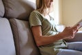 Unrecognizable woman reading a book on the sofa at home. Concept of new normality.