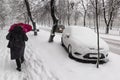 Unrecognizable woman with red umbrella walking on the city street during heavy winter snowfall. Royalty Free Stock Photo