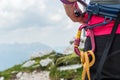 Unrecognizable woman rock climber wearing in safety harness with quickdraws and climbing equipment outdoor.