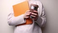 Unrecognizable woman in sweater holding book and reusable coffee cup