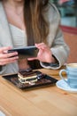 Unrecognizable woman taking photo of cake with her phone before eating it. Royalty Free Stock Photo