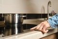 Unrecognizable woman turns on electric stove with touch control