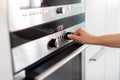 Unrecognizable Woman Using Electic Oven In Kitchen, Adjusting Temperature With Hand Royalty Free Stock Photo