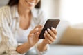 Unrecognizable Woman Using Modern Smartphone While Sitting On Couch At Home