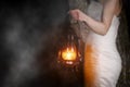 Unrecognizable Woman with Vintage Lantern Outside at Night. Young woman in white long dress walking in night wood.