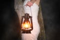 Unrecognizable Woman with Vintage Lantern Outside at Night. Young woman in white long dress walking in night wood.