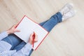 Unrecognizable woman writing in a red diary in a relaxed pose