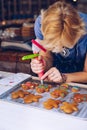 Unrecognizable women confectioner hand decorating a gingerman with a pastry bag, drawing a smile, making it cute, fun and