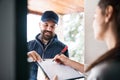 Woman receiving parcel from delivery man at the door.