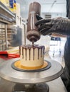 cake designer decorating a chocolate drip cake with mering and blueberries Royalty Free Stock Photo