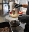 cake designer decorating a chocolate drip cake with mering and blueberries Royalty Free Stock Photo