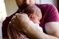 Unrecognizable young father at home holding his newborn baby gir