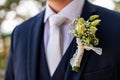 Unrecognizable young groom in elegant dark blue suit with beautiful white roses boutonniere. Groom fashion detail shot.