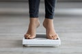 Unrecognizable young Indian lady checking her weight, standing on scales indoors, closeup of feet Royalty Free Stock Photo