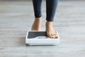 Unrecognizable young Indian woman stepping on scales to measure her weight at home, closeup of feet Royalty Free Stock Photo