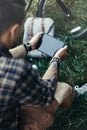 Unrecognizable Young Man Cyclist Sits On Summer Meadow Near Bicycle, Holding And Looking At Tablet Recreation Resting Travel