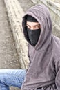 Unrecognizable young man wearing black balaclava sitting on old Royalty Free Stock Photo