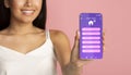 Unrecognizable young woman advertising smarthome mobile app on phone over pink background, collage