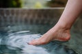 Unrecognizable young woman is dipping her foot in cool water of pond, refreshing and hardening concept. Royalty Free Stock Photo